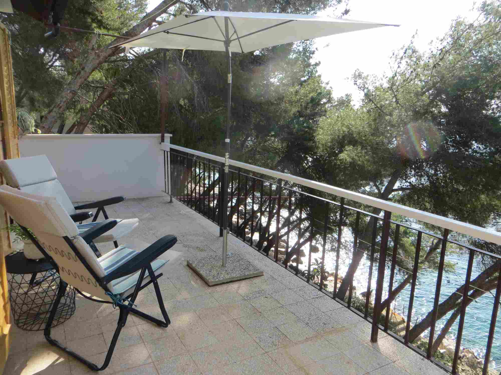 upper terrace of Villa V with lounge chairs and sunshade, with seaside below